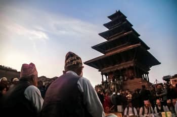 We see residents dressed in traditional attire assembled in prayer at dusk in front of the five-storey Pagoda style roof of the Nyatapola Temple in Bhaktapur.