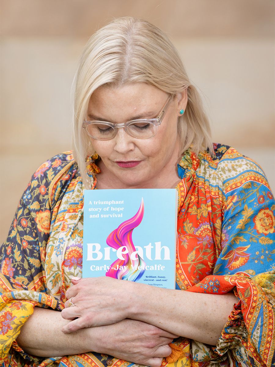 An image of Carly-Jay Metcalfe standing with her new book, Breath.
