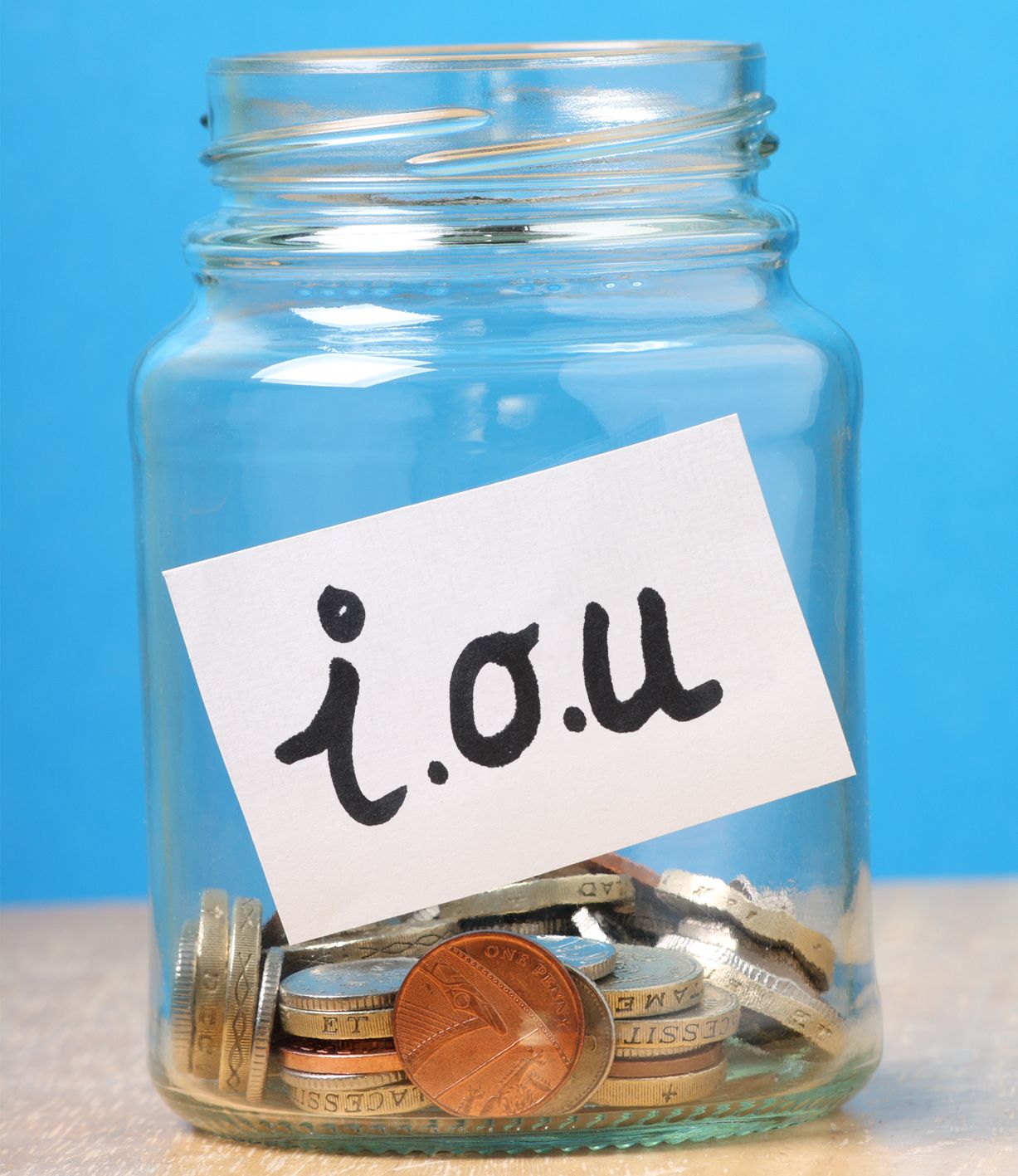 Jar of coins with white paper on front with the letters "i.o.u"